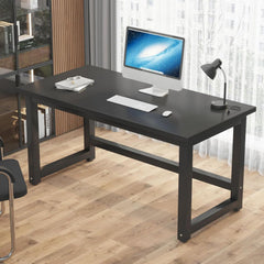 Black desk with computer setup on a wooden floor
